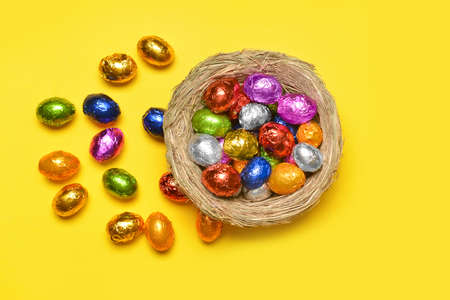 Nest with sweet chocolate eggs on color backgroundの写真素材