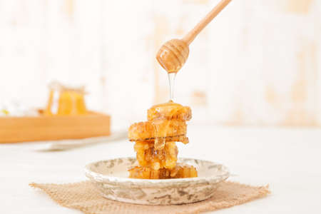 Honey dripping from dipper on tasty honeycombsの写真素材