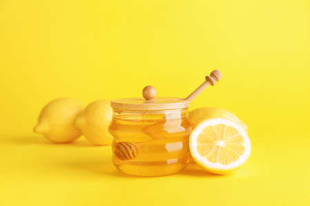Jar of sweet honey and lemon on color backgroundの写真素材