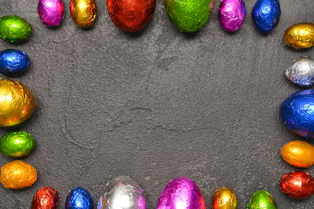Frame made of sweet chocolate eggs on gray background