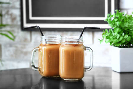 Mason jars of tasty iced coffee on table in cafeの写真素材