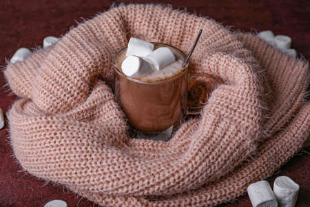 Cup of hot chocolate with marshmallows and scarf on tableの写真素材