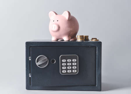 Modern safe with piggy bank and coins on light backgroundの写真素材