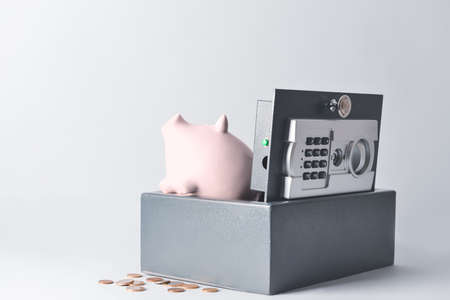 Modern safe with piggy bank and coins on light backgroundの写真素材