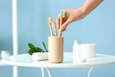 Woman taking wooden tooth brush from holder in bathroomの写真素材