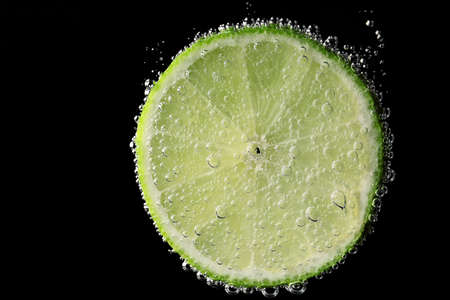 Fresh lime piece under water on dark backgroundの写真素材