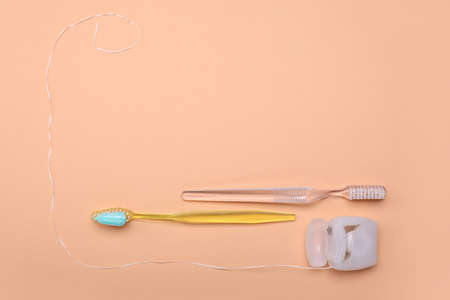 Tooth brushes with paste and dental floss on color backgroundの写真素材