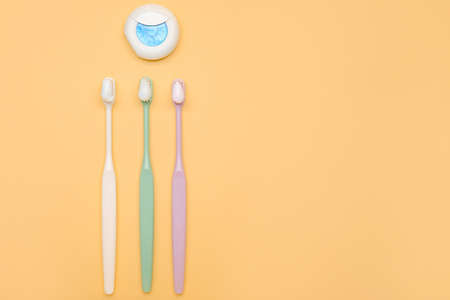 Tooth brushes with paste and dental floss on color backgroundの写真素材
