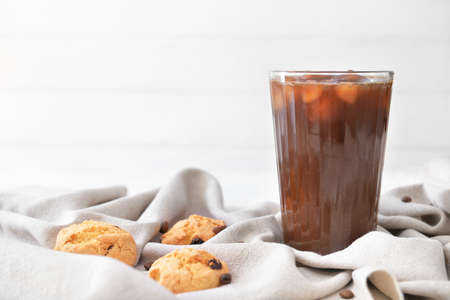 Glass of tasty iced coffee with cookies on tableの写真素材