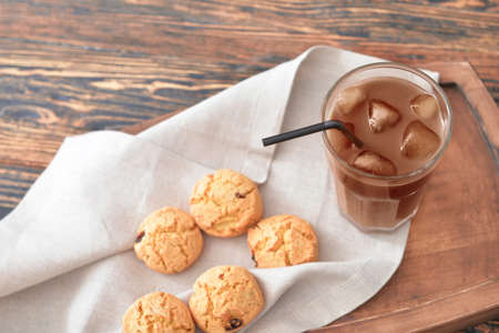 Glass of tasty iced coffee with cookies on tableの写真素材