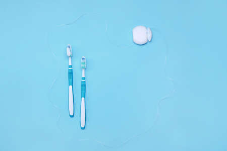Tooth brushes with paste and dental floss on color backgroundの写真素材