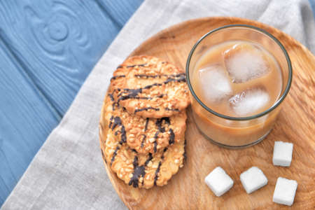Glass of tasty iced coffee with cookies on tableの写真素材