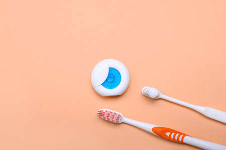 Tooth brushes with paste and dental floss on color backgroundの写真素材