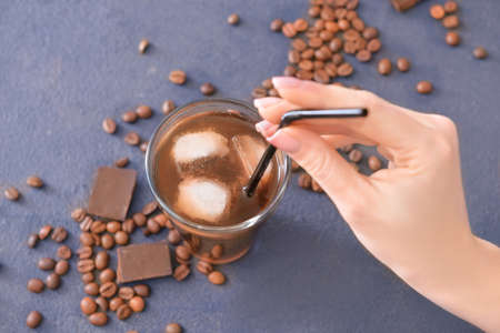 Female hand with glass of tasty iced coffee on dark backgroundの写真素材