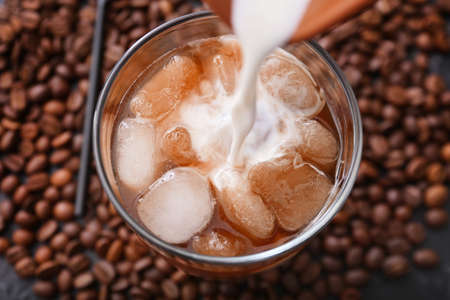 Pouring of milk into cold coffee in glass, closeupの写真素材