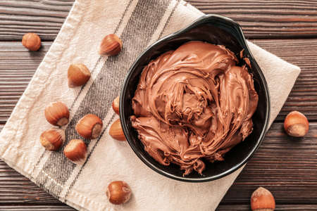 Bowl with tasty chocolate paste and hazelnuts on tableの写真素材