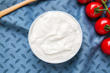 Bowl with tasty sour cream and tomatoes on tableの写真素材