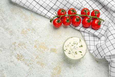 Bowl with tasty sour cream and tomatoes on tableの写真素材