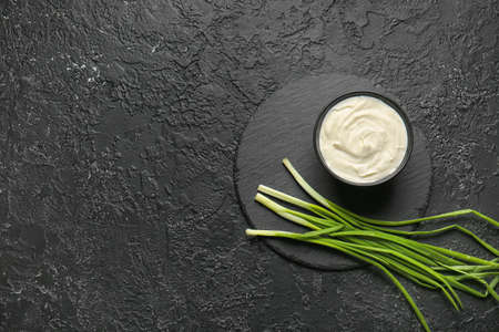 Bowl with tasty sour cream and green onion on tableの写真素材