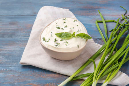 Bowl with tasty sour cream and green onion on tableの写真素材