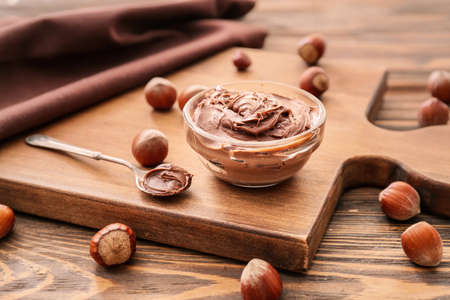 Bowl with tasty chocolate paste and hazelnuts on tableの写真素材