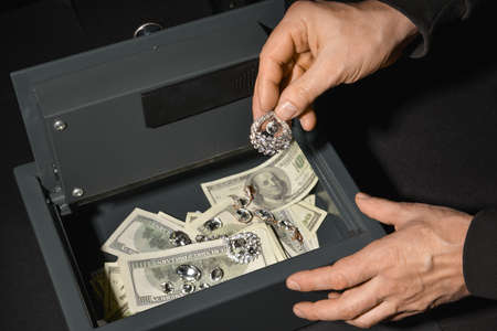 Burglar stealing valuables from safe box, closeupの写真素材