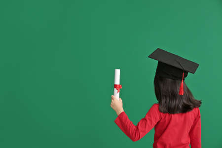 Little girl in graduation hat and with diploma on color backgroundの写真素材