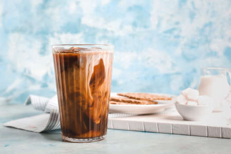 Glass of tasty cold coffee on color background