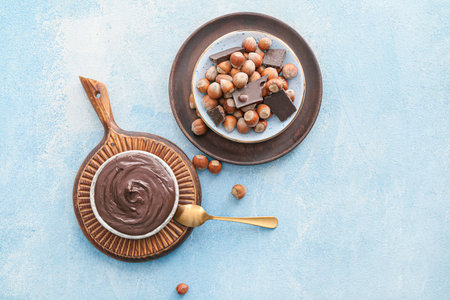Plates with tasty chocolate paste and hazelnuts on color backgroundの写真素材