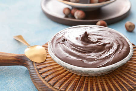Plate with tasty chocolate paste and hazelnuts on color backgroundの写真素材