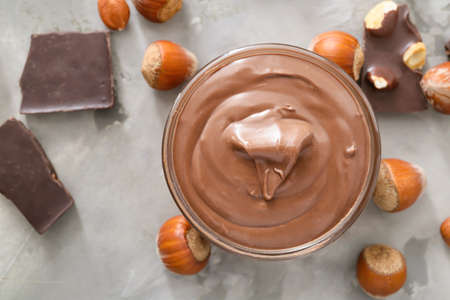 Bowl with tasty chocolate paste and hazelnuts on gray backgroundの写真素材
