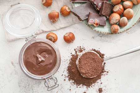 Jar with tasty chocolate paste and hazelnuts on light backgroundの写真素材
