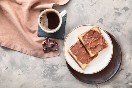 Plate with fresh bread, chocolate paste and cup of coffee on grunge backgroundの写真素材