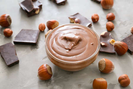 Bowl with tasty chocolate paste and hazelnuts on gray backgroundの写真素材