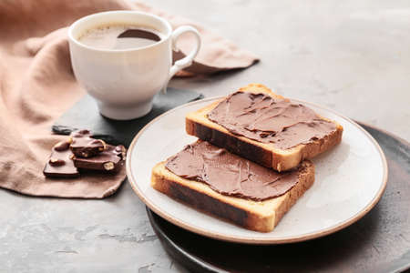Plate with fresh bread, chocolate paste and cup of coffee on grunge backgroundの写真素材