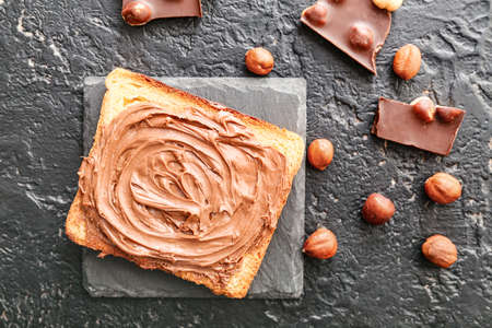 Fresh bread with chocolate paste and hazelnuts on dark backgroundの写真素材