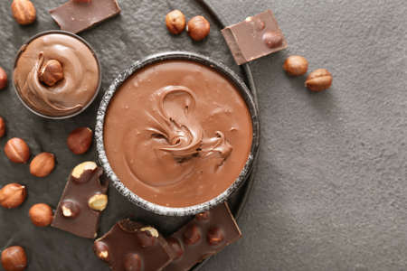 Bowls with tasty chocolate paste and hazelnuts on gray backgroundの写真素材