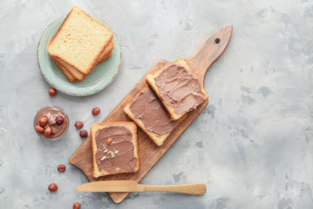Board with fresh bread and chocolate paste on gray backgroundの写真素材