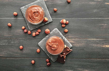 Bowls with tasty chocolate paste and hazelnuts on tableの写真素材