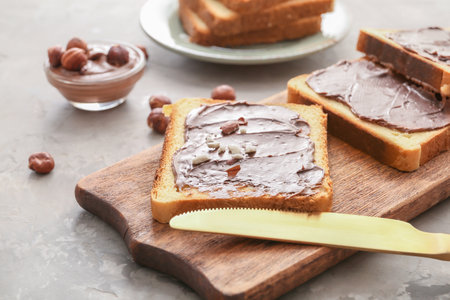 Board with fresh bread and chocolate paste on gray backgroundの写真素材