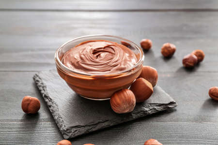 Bowl with tasty chocolate paste and hazelnuts on tableの写真素材