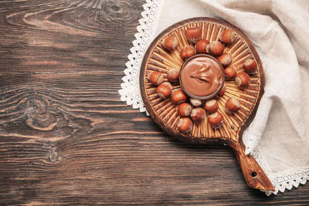 Bowl with tasty chocolate paste and hazelnuts on tableの写真素材