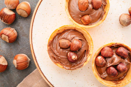 Tartlets with tasty chocolate paste and hazelnuts on plate