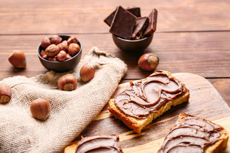 Board with fresh bread and chocolate paste on tableの写真素材