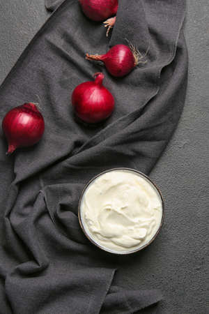 Bowl of tasty sour cream and onion on tableの写真素材