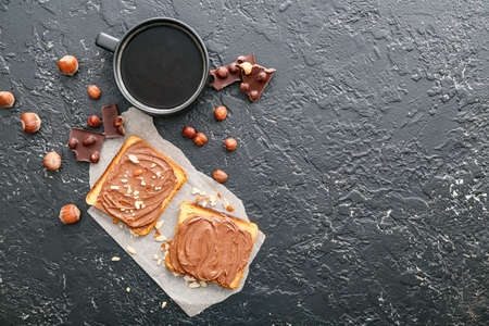 Fresh bread with chocolate paste and cup of coffee on dark backgroundの写真素材