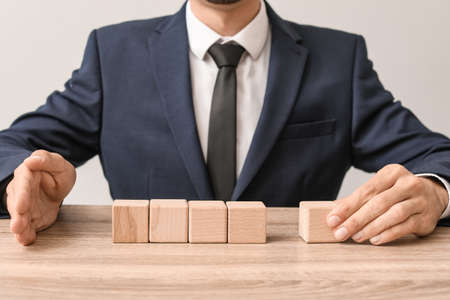 Man removing wooden cube from table. Concept of dismissalの写真素材