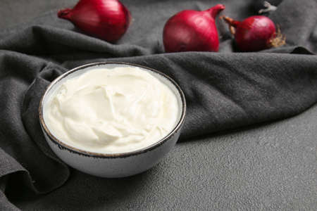 Bowl of tasty sour cream and onion on tableの写真素材