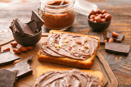 Board with fresh bread and chocolate paste on tableの写真素材