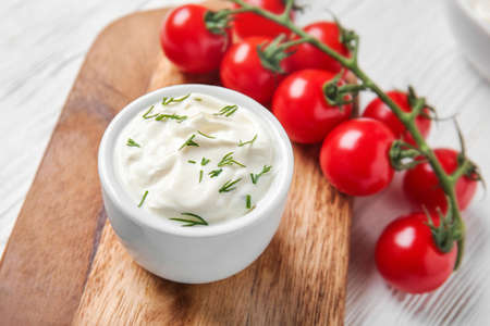 Tasty sour cream and tomatoes on white wooden tableの写真素材